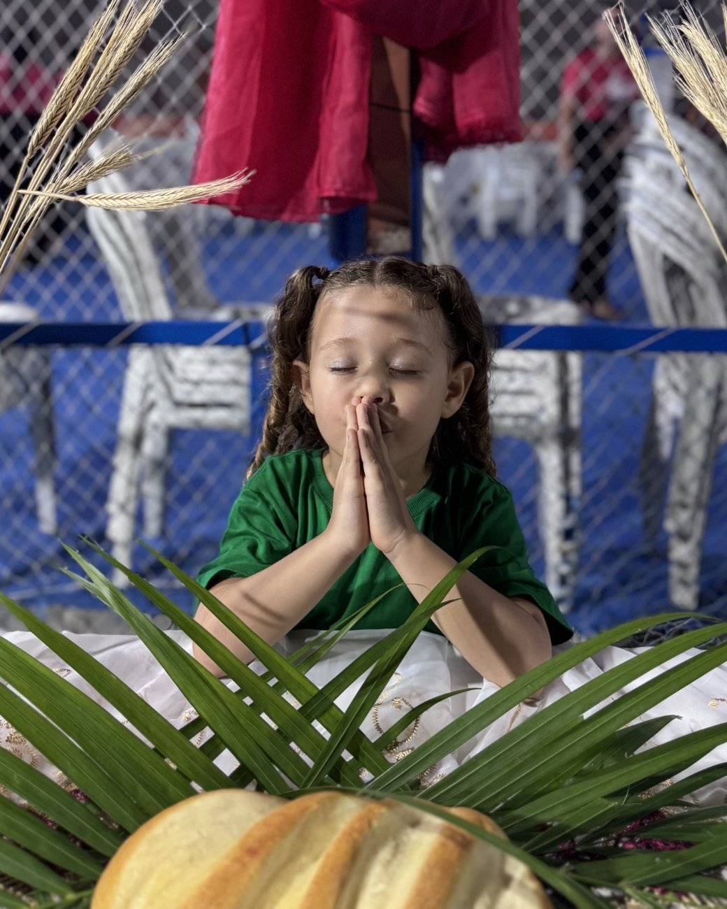 Crianca em oracao durante o Momentinho com Deus, na atividade biblica da escola