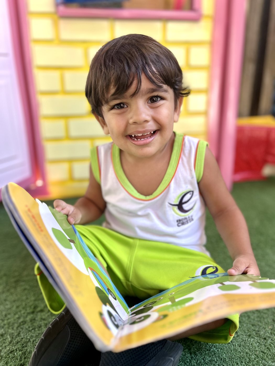 Criança do Berçário folheando um livro no parque
